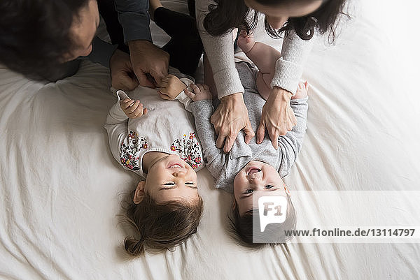 Hochwinkelaufnahme von spielenden Eltern  die Kinder zu Hause im Bett kitzeln