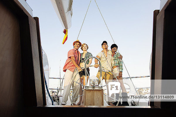 Happy couples standing by steering wheel on nautical vessel