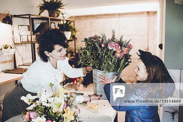 Florist schenkt Mädchen im Laden einen Eimer Blumen