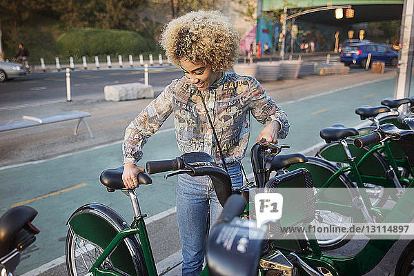 Glückliche Frau mietet Fahrrad auf der Straße in der Stadt