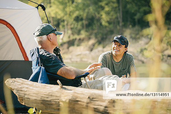Männliche Freunde unterhalten sich beim Entspannen auf dem Campingplatz