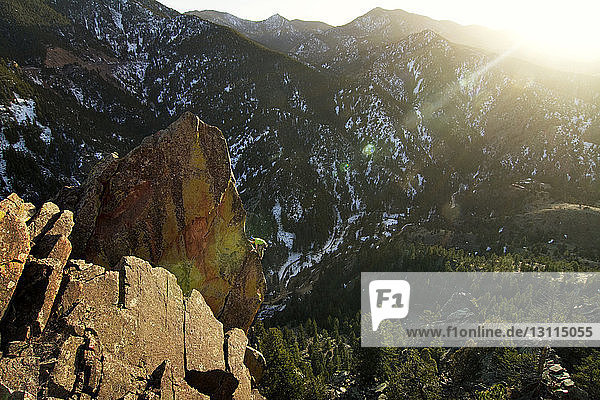 Man climbing rock mountain on sunny day