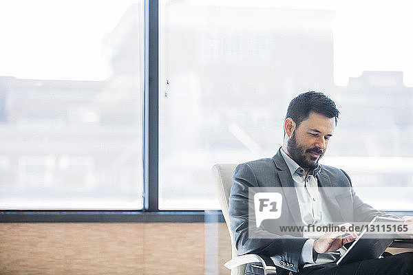 Businessman using tablet computer by window in office