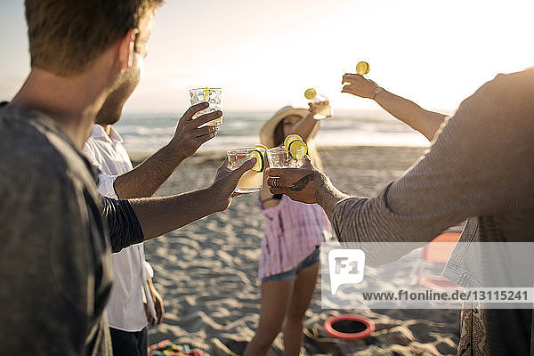 Fröhliche Freunde stoßen am Strand auf Getränke an