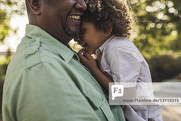 Midsection of happy father embracing son while standing at park