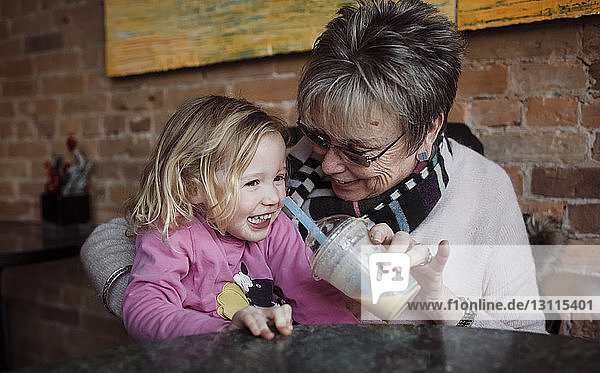 Glückliche Großmutter füttert Enkelin  während sie zu Hause sitzt