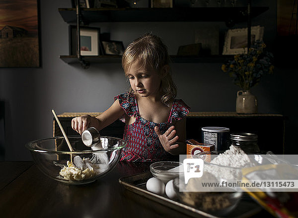 Mädchen bereitet zu Hause süße Speisen auf dem Tisch zu