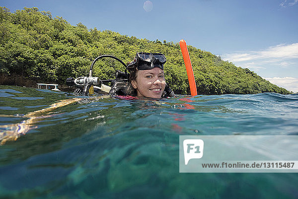Portrait of happy female diver with snorkeling equipment in sea