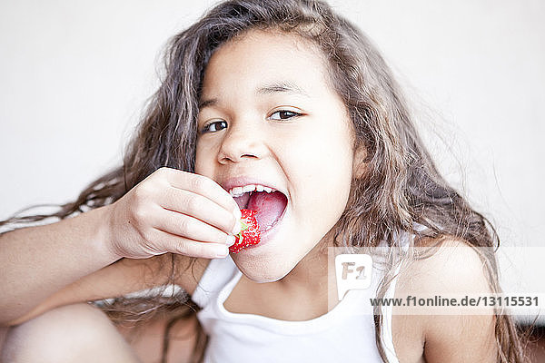 Porträt eines glücklichen Mädchens  das zu Hause Erdbeeren isst
