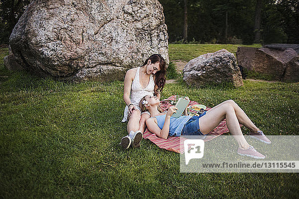 Happy lesbian couple relaxing on grassy field at park
