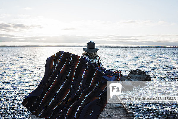 Rückansicht einer Frau mit Decke  die auf einem Pier am Simcoe-See gegen den Himmel steht