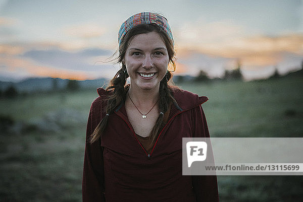 Porträt einer glücklichen Frau  die bei Sonnenuntergang auf dem Feld steht