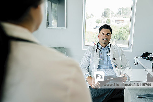 Arzt betrachtet Kollegin bei der Arbeit im Krankenhaus