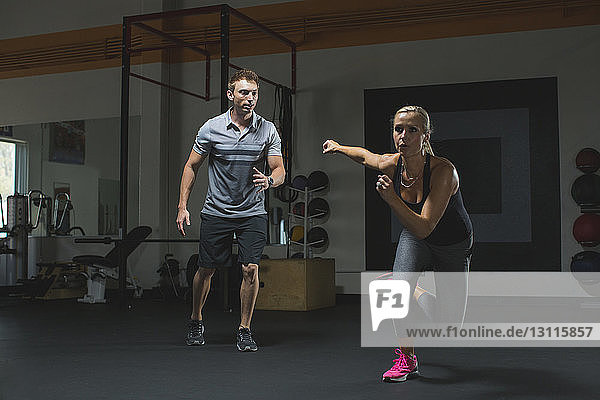 Trainer betrachtet weibliche Kunden beim Training im Fitnessstudio