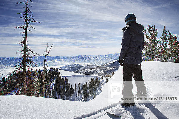 Skifahrer steht auf schneebedecktem Wasatch Mountain vor bewölktem Himmel
