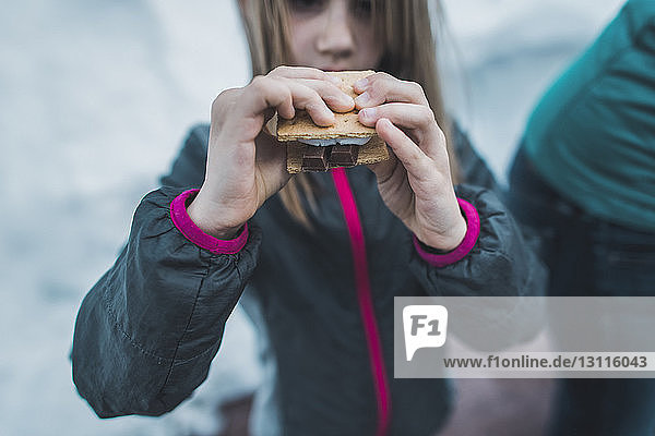 Midsection of girl holding smore on snowy field