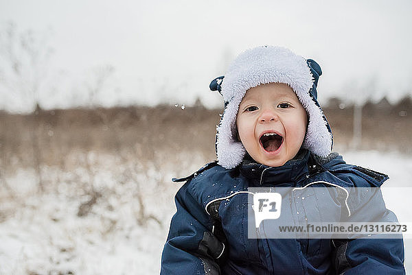 Portrait of cute playful baby boy shouting while wearing warm clothing during winter