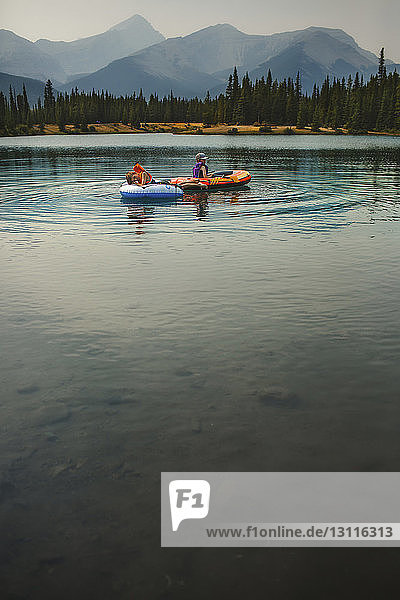Brothers rafting on lake against mountains