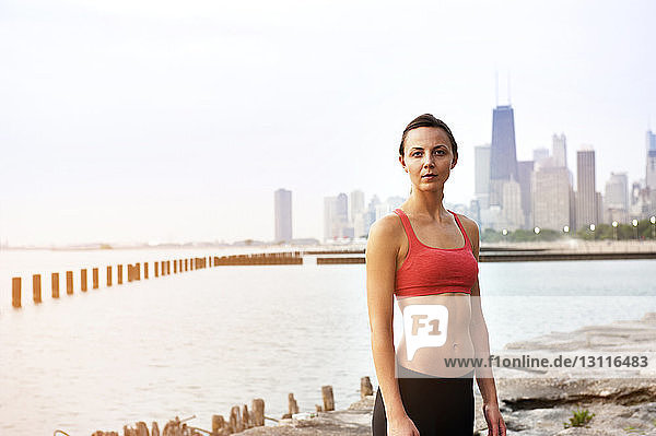 Portrait of female athlete standing at beach in city