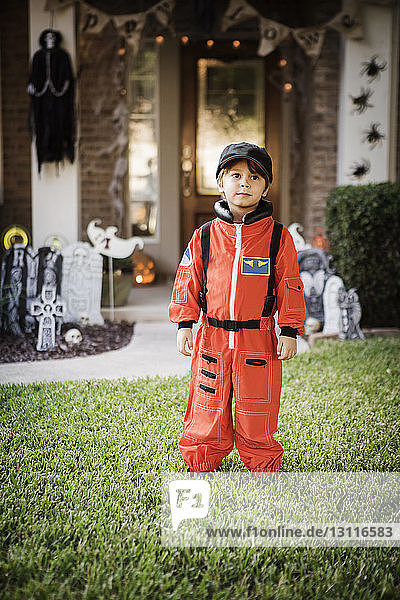 Junge in Astronautenkostüm steht auf Gras vor dem Haus