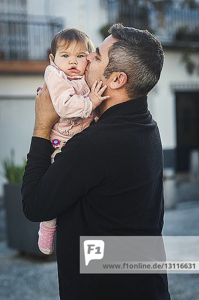 Side view of Father kissing baby girl outdoors
