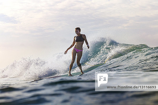 Frau in voller Länge beim Surfen auf See