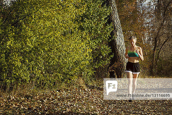 Woman jogging on field by forest