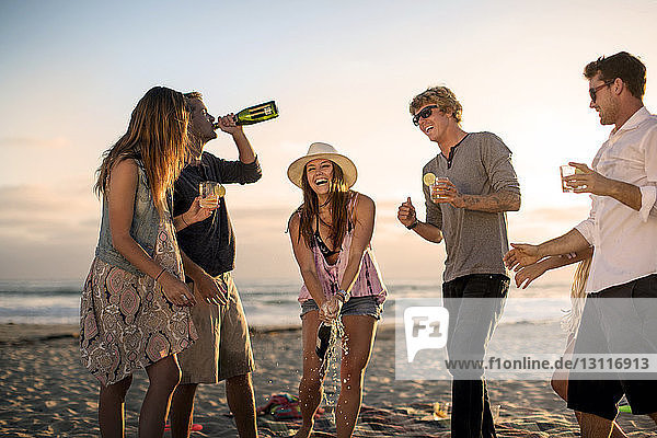 Happy friends enjoying drinks on beach