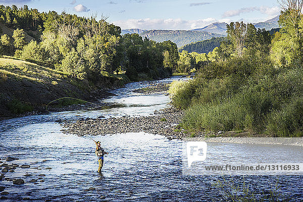 Mann fischt im Fluss inmitten der Felder