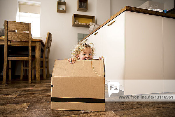 Portrait of happy girl sitting in cardboard box at home