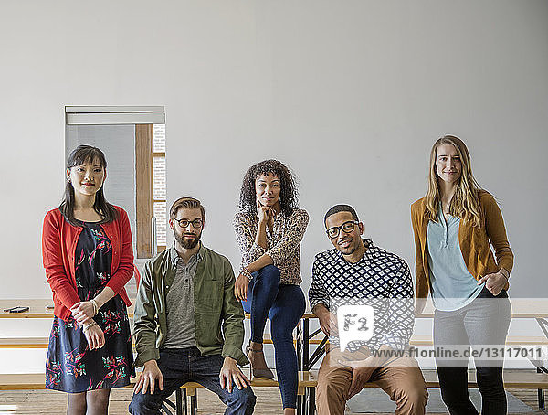 Portrait of confident business people against wall at creative office