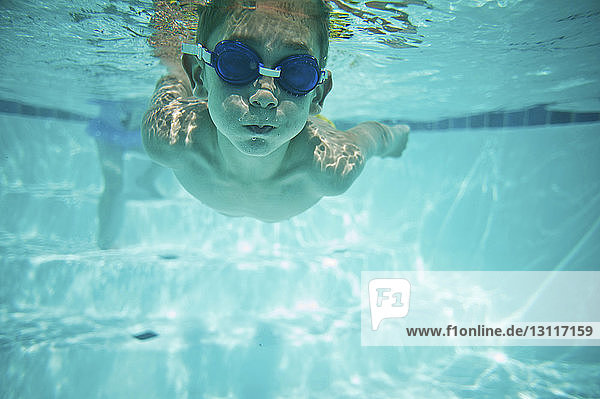 Junge ohne Hemd schwimmt unter Wasser im Pool