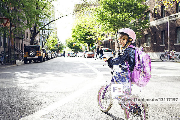 Side view of happy girl riding bicycle on street