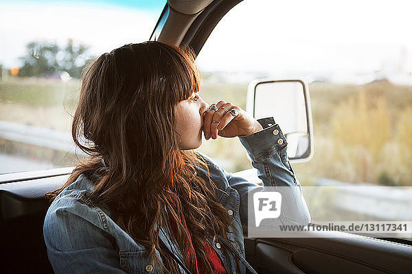Thoughtful woman travelling in camper van looking out window