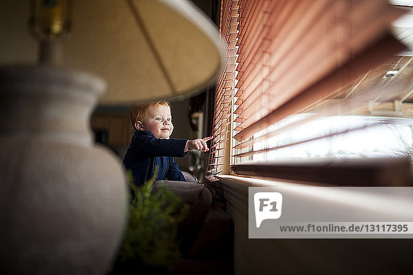 Baby boy playing with window blinds at home