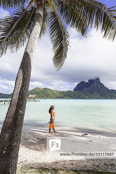 Frau in voller Länge in traditioneller Kleidung am Strand gegen den Himmel stehend