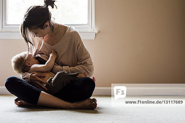 Woman breastfeeding son while sitting at home