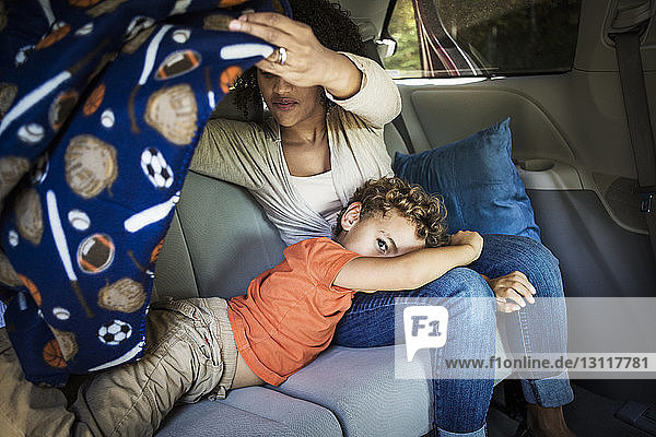 Mutter deckt Sohn mit Decke im Auto zu