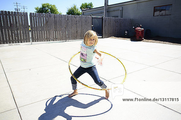 Porträt eines Mädchens  das im Sommer auf dem Spielplatz mit Hula-Hoop-Reifen spielt