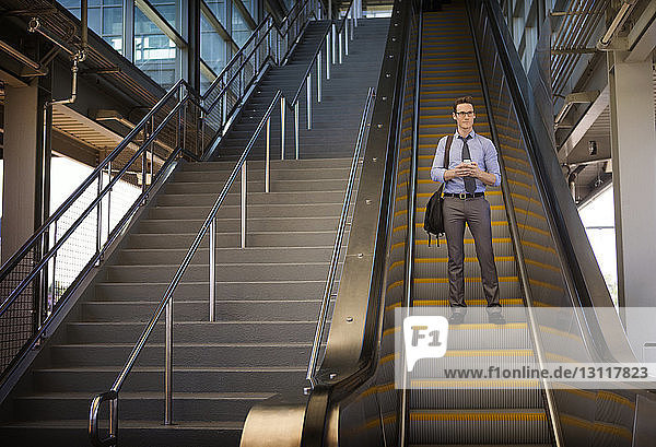 Low angle view of businessman standing on escalator