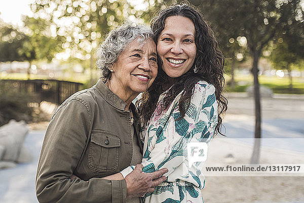 Porträt einer glücklichen Tochter  die eine ältere Mutter im Park umarmt