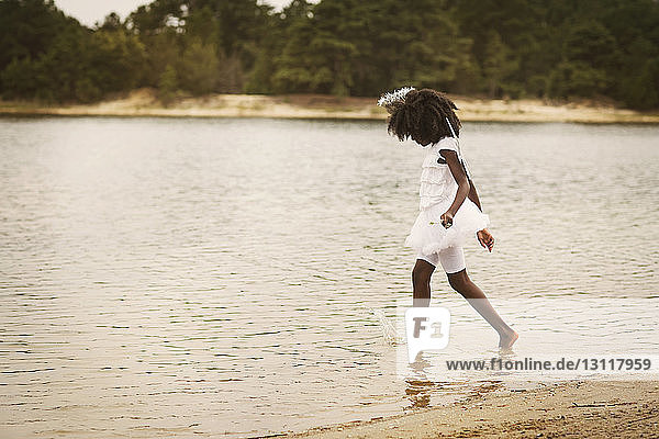 Seitenansicht eines als Engel verkleideten Mädchens beim Spaziergang am See