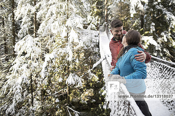 Ehepaar steht im Winter auf einem Steg inmitten des Waldes im Lynn Canyon Park