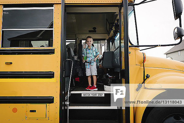 Porträt eines Jungen mit Rucksack im Schulbus stehend