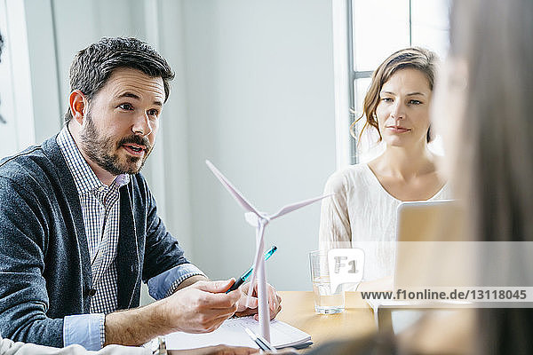 Business people discussing about wind turbine model in office