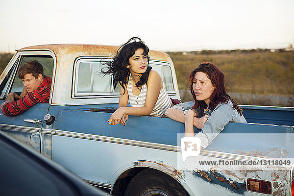 Thoughtful friends leaning out while traveling in pick-up truck