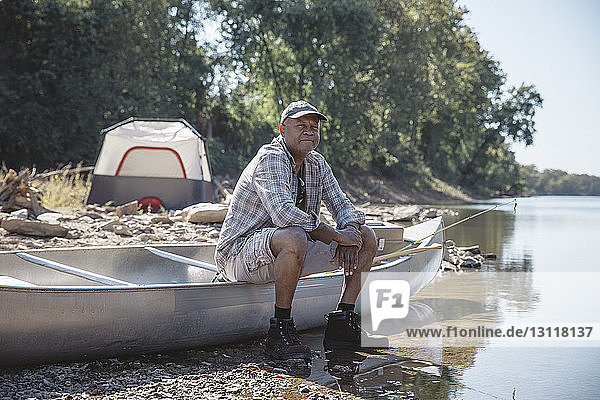 Porträt eines Mannes  der auf einem Boot am Seeufer sitzt