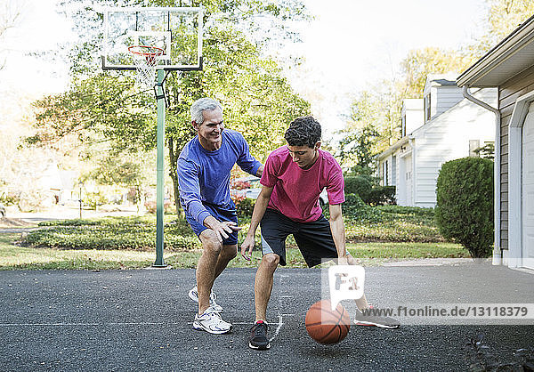 Grandfather playing basketball with grandson at backyard