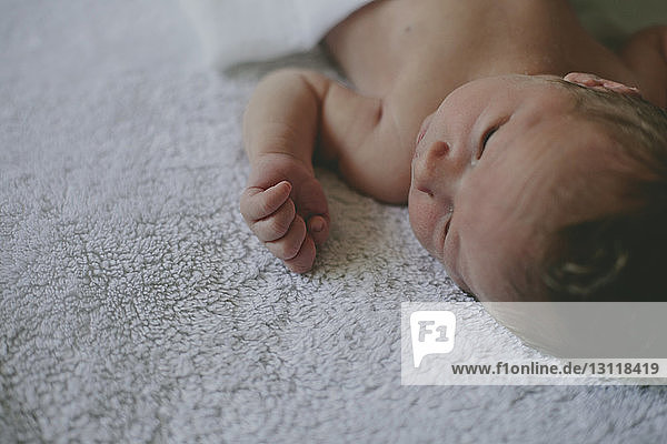 Close-up of cute baby lying on blanket in bed