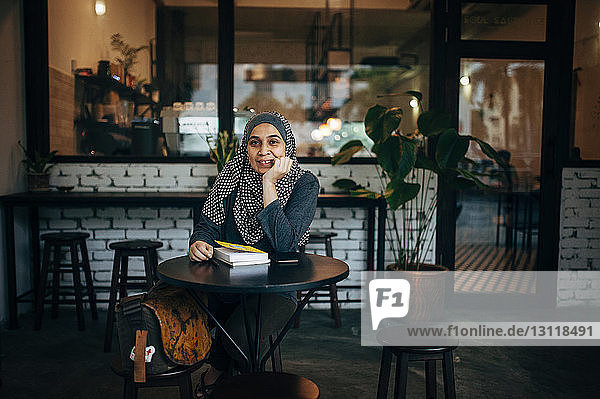 Porträt einer Frau mit Büchern im Cafe sitzend